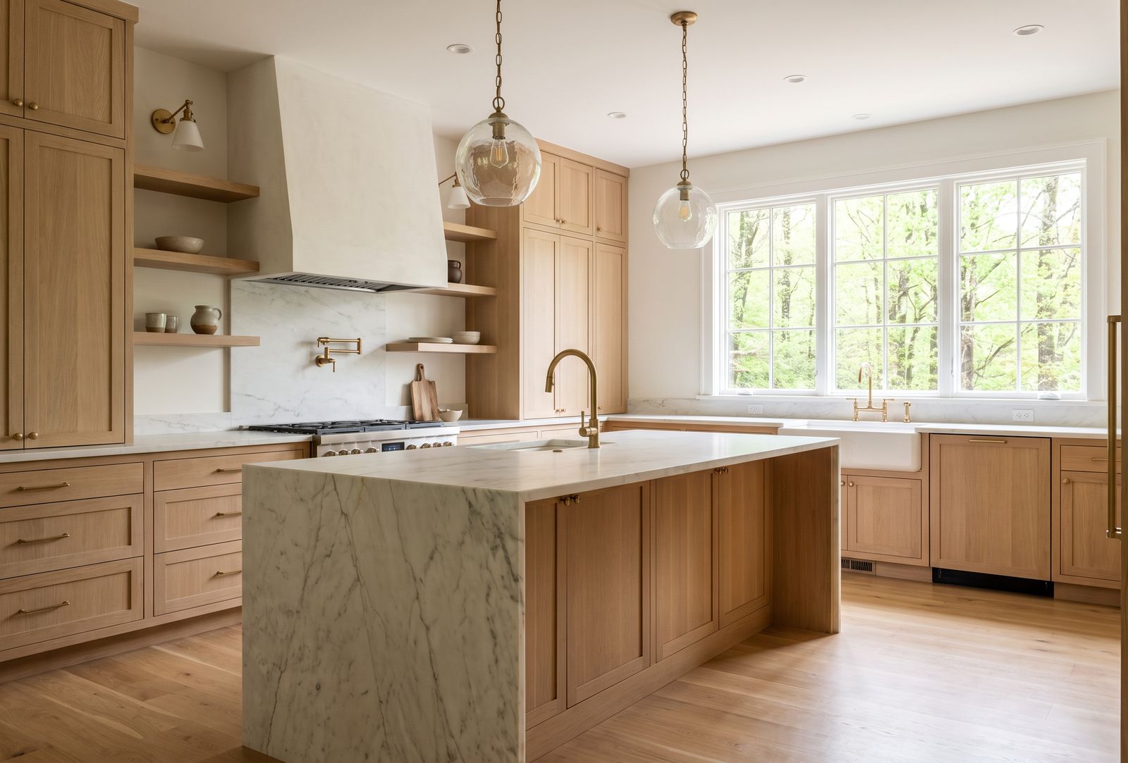 Remodeled kitchen with white oak cabinetry, a marble waterfall island and glass pendants